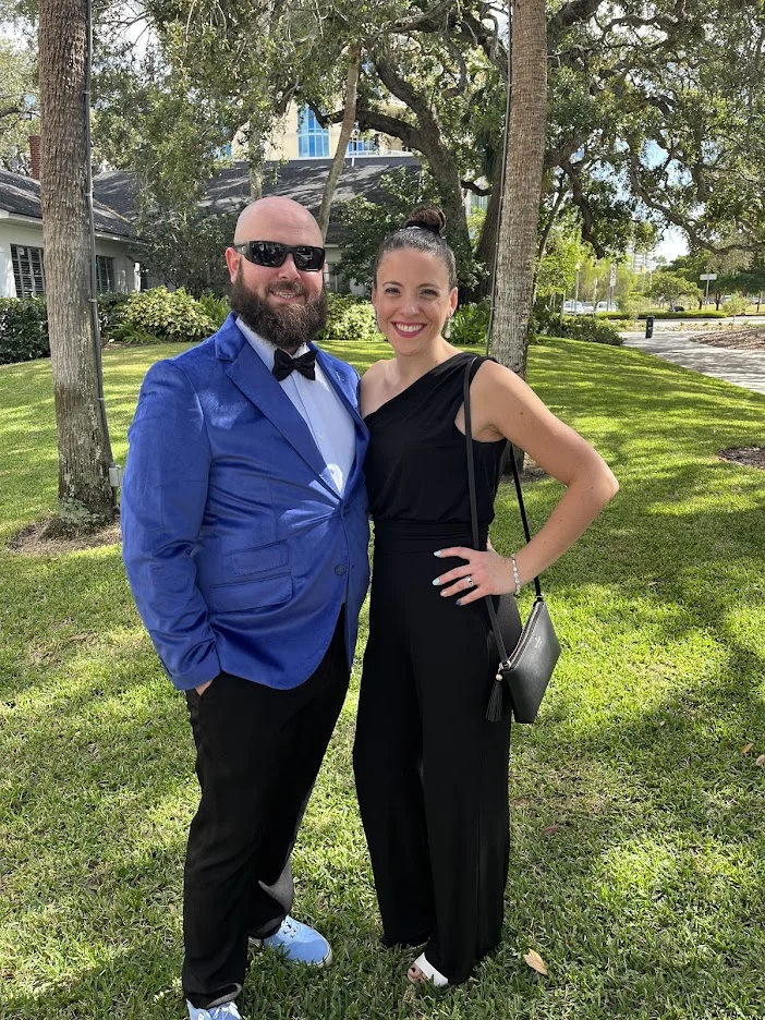Kyle in a blue suit and his wife in a black dress
