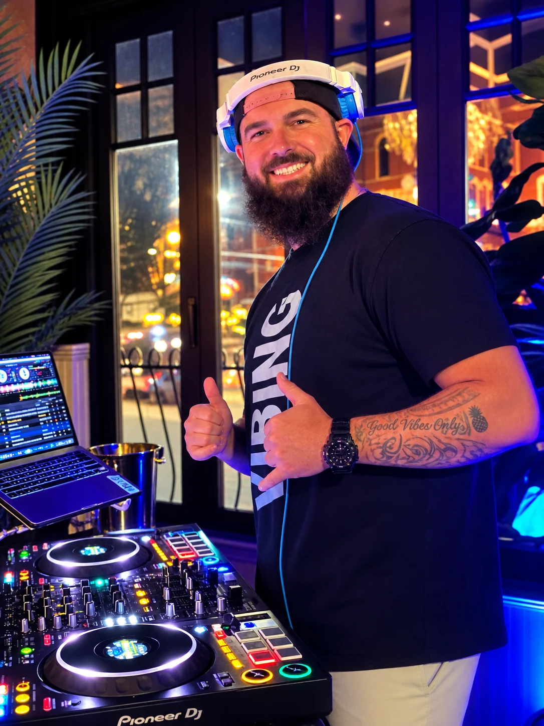 Kyle, DJ Good Vibes, smiling at the decks with blue headphones